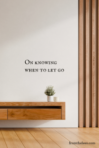 A minimalist wooden console with a small potted plant and candle against a cream colored wall beside the words, "On knowing when to let go." Clean lines, warm wood tones, and open space create a calm, contemplative scene that evokes simplicity, acceptance, and quiet release.